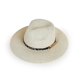 Detailed macro view of leopard print ribbon and gold buckle on a beige straw sun hat
