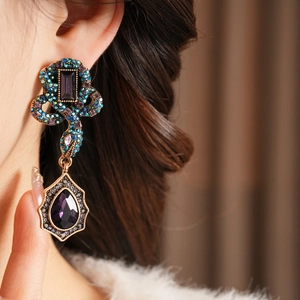 Boucles d'oreilles serpent vintage avec strass violets et pierres en goutte sur le modèle