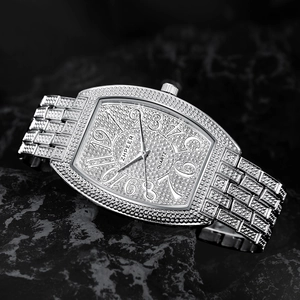 Macro detail of silver iced-out tonneau watch with quartz movement on dark rock base