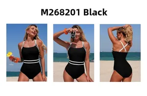 Close-up of black one-piece swimsuit with white trim and cross-back straps on beach