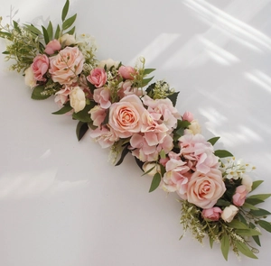 Detail of pink and cream artificial rose flower row with green leaves and gypsophila