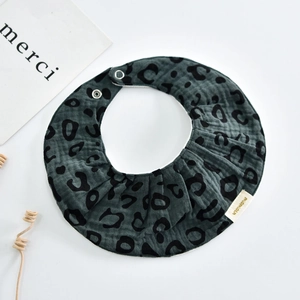 Detail of baby leopard print cotton bib with gauze texture and adjustable snaps