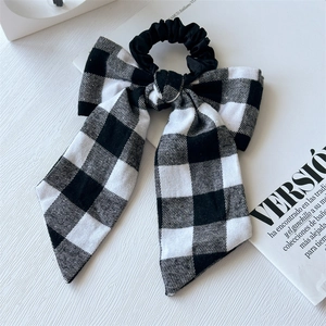 Detail of black and white checkered bow hair scrunchie with long ribbons on a magazine
