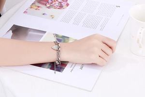 Gros plan d'un bracelet double couche en acier inoxydable avec pendentif cœur au poignet