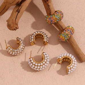 Detailed view of three pairs of C-shaped earrings with gold plating, rhinestones and pearls