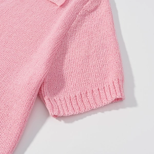 Detailed macro shot of pink knit top showing soft fabric texture and ribbed cuff detail