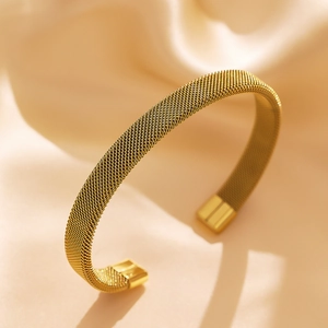 Detailed close-up of gold mesh woven cuff bracelet on elegant silk background