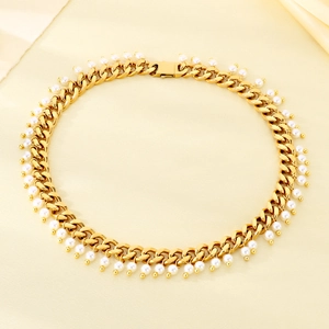 Detail of 9mm gold Cuban chain necklace with white pearl pendants on beige silk fabric
