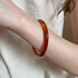 Close-up of a retro amber resin bangle with tortoiseshell texture on woman's wrist