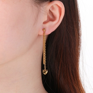 Detailed view of long 18K gold plated chain earrings with heart pendants on a model