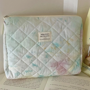 Detailed macro view of quilted watercolor makeup bag featuring pastel gradient patterns