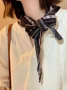 Detail of vintage striped fabric scarf necklace with floral patterns tied in a bow