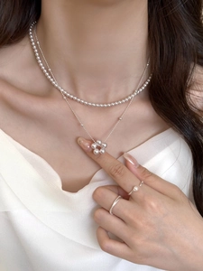 Gros plan d'un collier fleur en perles et bagues empilables sur un mannequin