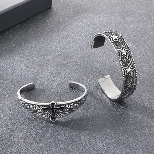 Detailed relief of vintage cross wings and star patterns on steel open cuff bracelets