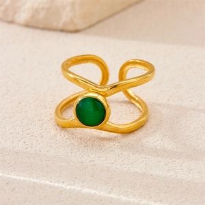 Macro detail of retro 18K gold plated ring with green gemstone on stone background