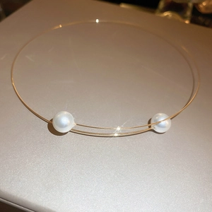 Detailed view of a gold geometric choker featuring two elegant large white pearls on each end