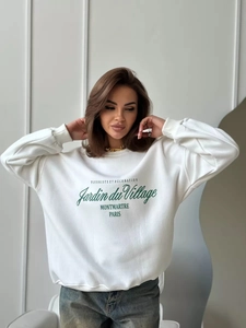 Λεπτομέρεια από λευκό oversized φούτερ με πράσινα γράμματα Jardin du Village και μαλακό βαμβάκι