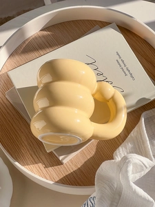 Detail of a creamy yellow bubble ceramic mug with a chunky handle on a wooden stand