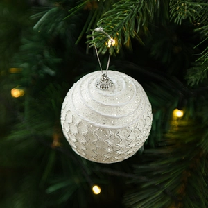 Close-up of white glitter Christmas ornament with wavy thread on a festive tree