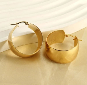 Gros plan de boucles d'oreilles créoles larges dorées polies avec une finition miroir