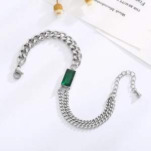 Detail view of emerald-green rectangular gem on a silver Cuban chain bracelet