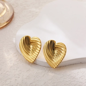 Dettaglio di orecchini a cuore d'oro 18k con strisce verticali su un piedistallo di pietra