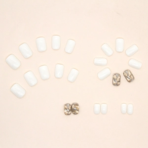 Unghie finte bianco crema con glitter champagne e strass su sfondo beige neutro