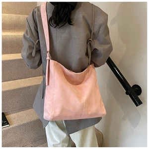 Detail of pink suede tote bag with adjustable strap worn by model in casual style