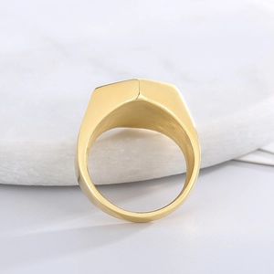 Minimalist gold plated hexagonal stainless steel signet ring on white stone display