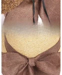Detailed view of the large brown ribbon bow on a woven straw sun hat for women