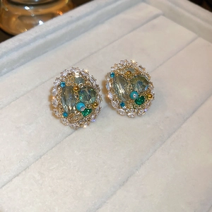 Macro detail of gold-plated geometric earrings with inlaid multicolor crystals and zircons