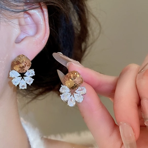 Detail of amber gemstone and pear-cut zircon cluster earrings shown on an ear
