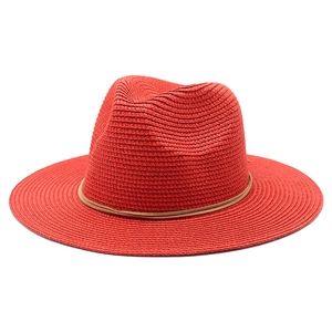 Close-up of red straw fedora sun hat featuring detailed weave and brown cord trim