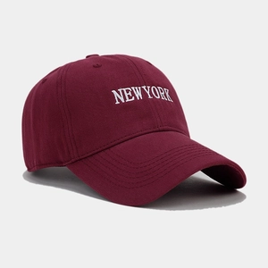 Detail view of New York embroidery on a burgundy cotton baseball cap with curved brim