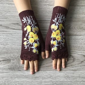 Detail of dark brown knit fingerless gloves with yellow floral embroidery and crochet trim