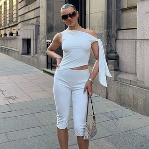 Detail von weißem One-Shoulder-Oberteil und schmaler Caprihose als Set für Damen