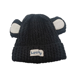 Détail du bonnet en maille noire avec oreilles d'ours et étiquette Lucky en tissu bleu