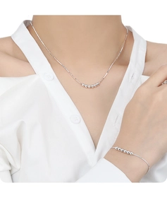 Détail de l'ensemble collier et bracelet à billes d'argent sur modèle au style minimaliste