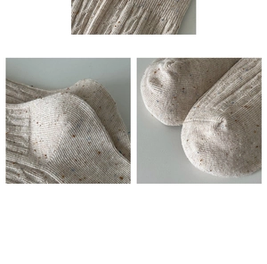Detail view of beige knit socks showing the fine stitching, texture, and colored speckles