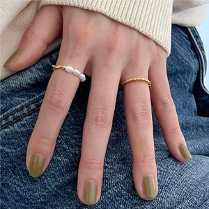 Detail of stacked gold twisted rope ring and pearl beaded ring on a hand