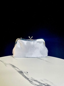 Silver satin evening clutch bag detail showcasing metal kiss-lock clasp and fabric texture.