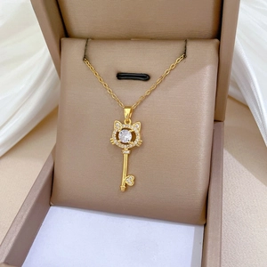 Detailed close-up of golden cat-ear key pendant with sparkling pavé zircons and heart tip