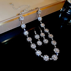 Détail d'un ensemble de bijoux floraux argentés avec cristaux brillants sur surface noire