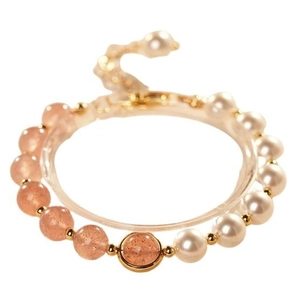 Elegant strawberry crystal and pearl beaded bracelet with gold accents on display