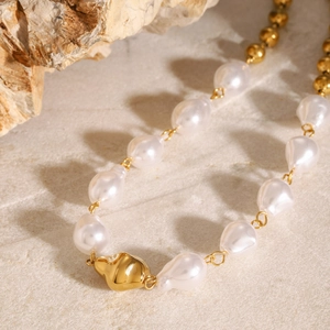 Elegant stainless steel necklace with baroque pearls and golden beads on stone surface