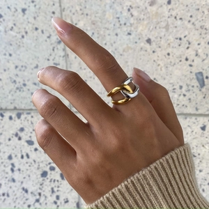 Close-up of interlocking gold and silver rings worn on finger with knit sweater detail
