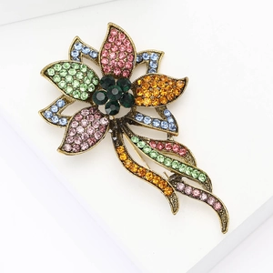 Vintage gold alloy flower brooch with colorful rhinestones on a white background
