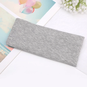 Close-up of a light grey knitted headband with ribbed texture and twisted knot detail