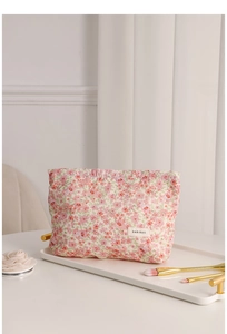 Detail of floral makeup bag featuring pink flower patterns and woven brand label