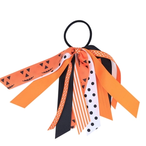 Detail of Halloween hair tie with orange pumpkin, polka dots, and striped ribbons